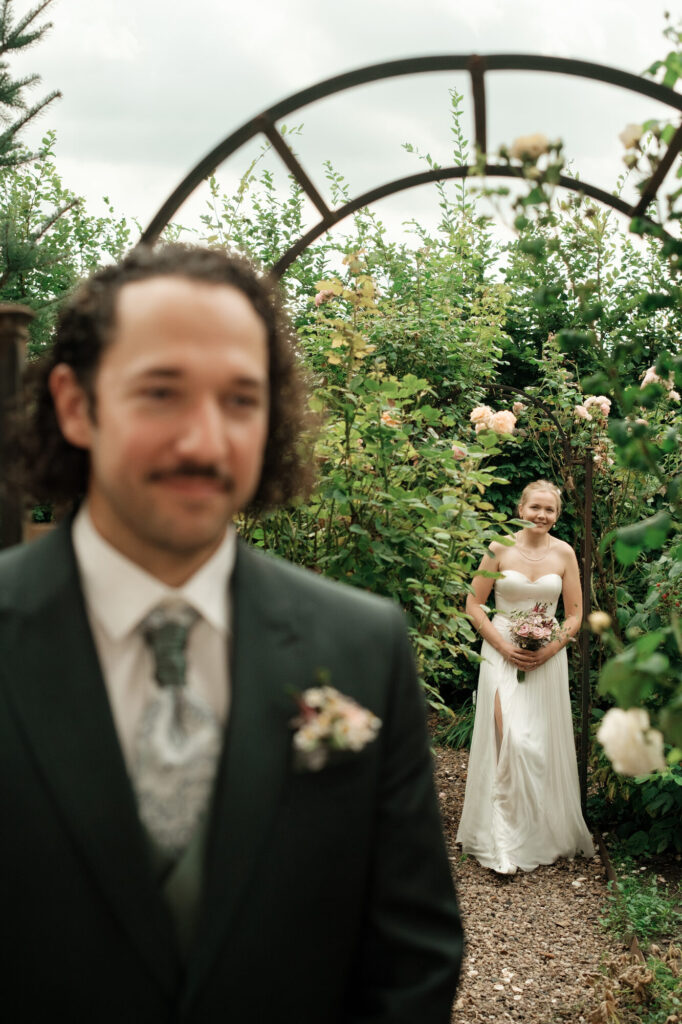 Braut kommt durch den Rosenbogen auf den Bräutigam zu, Hochzeit Anne & Phil auf dem Hof Gottschalk in Helpsen