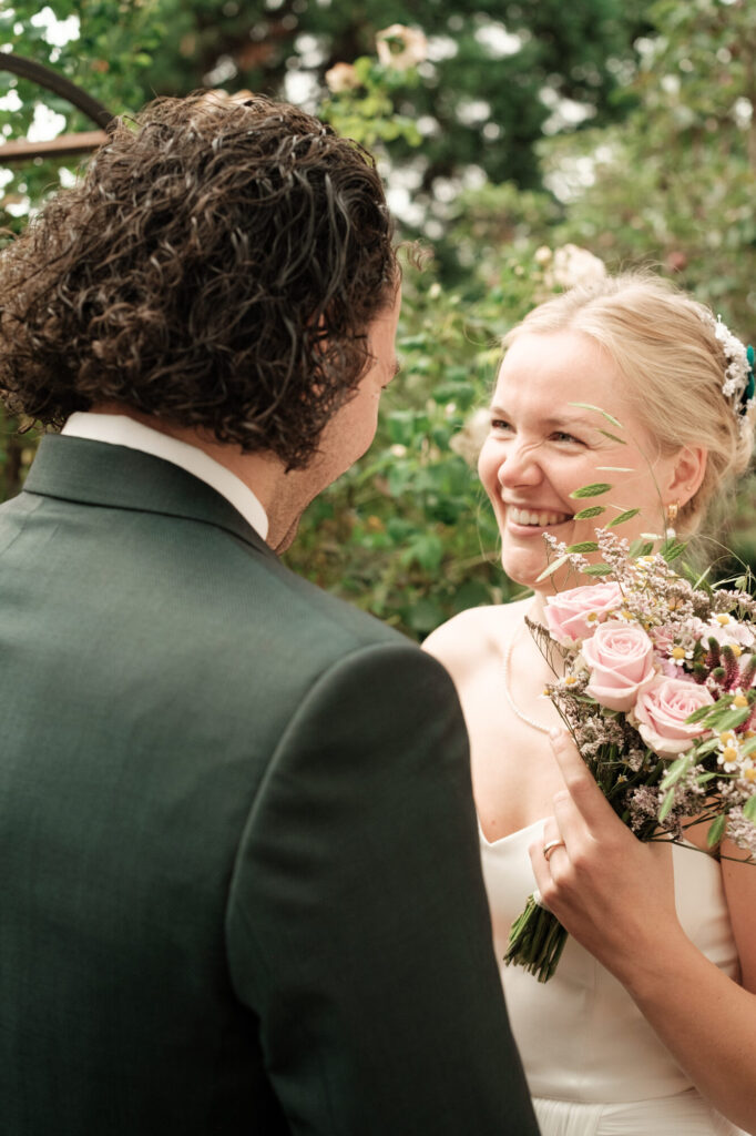 Braut lacht beim ersten Blick, Brautstrauß in der Hand, Hochzeit Anne & Phil auf dem Hof Gottschalk in Helpsen