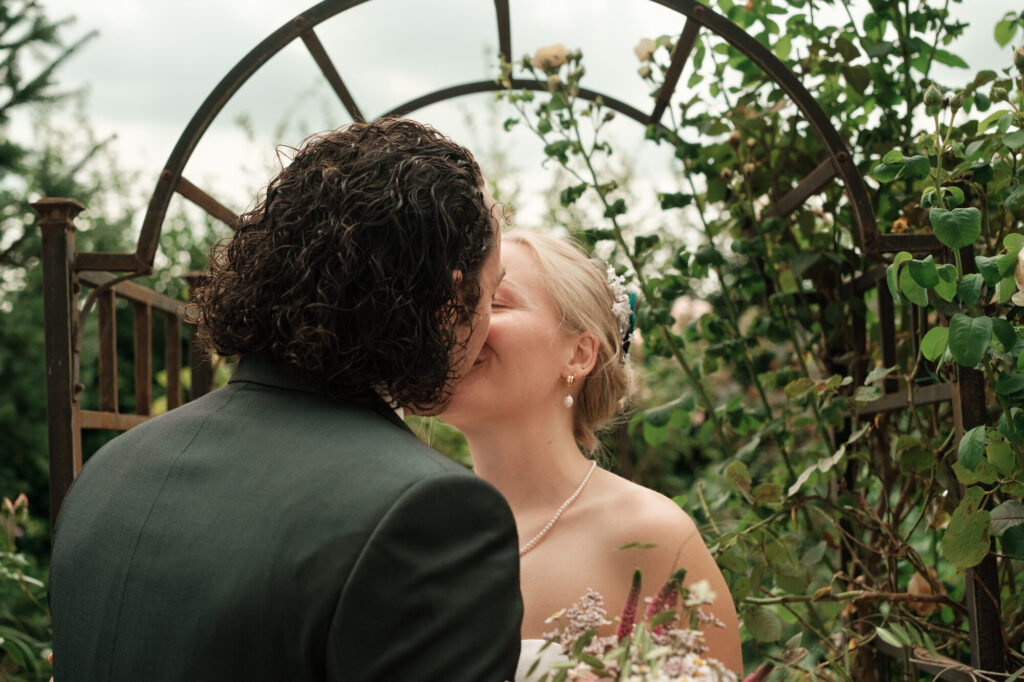 Kuss beim ersten Blick unter dem Rosenbogen, Hochzeit Anne & Phil auf dem Hof Gottschalk in Helpsen