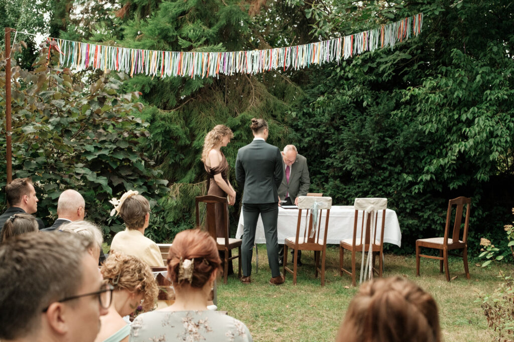 Standesamtliche Trauung im Garten mit den Gästen, Hochzeit Anne & Phil auf dem Hof Gottschalk in Helpsen