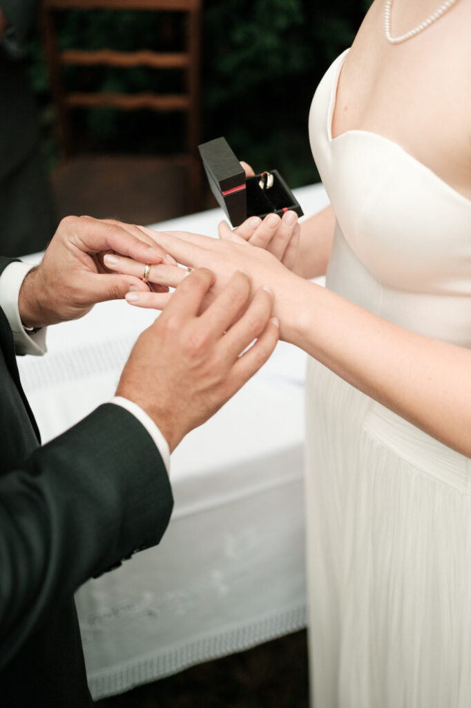 Bräutigam steckt der Braut den Ring an, Hochzeit Anne & Phil auf dem Hof Gottschalk in Helpsen