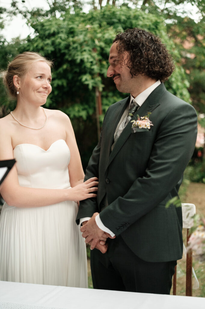 Brautpaar lächelt sich am Trautisch an, Hochzeit Anne & Phil auf dem Hof Gottschalk in Helpsen
