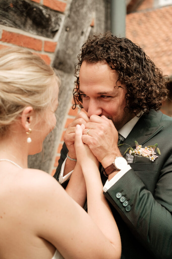 Bräutigam lacht und küsst die Hände der Braut, Hochzeit Anne & Phil auf dem Hof Gottschalk in Helpsen