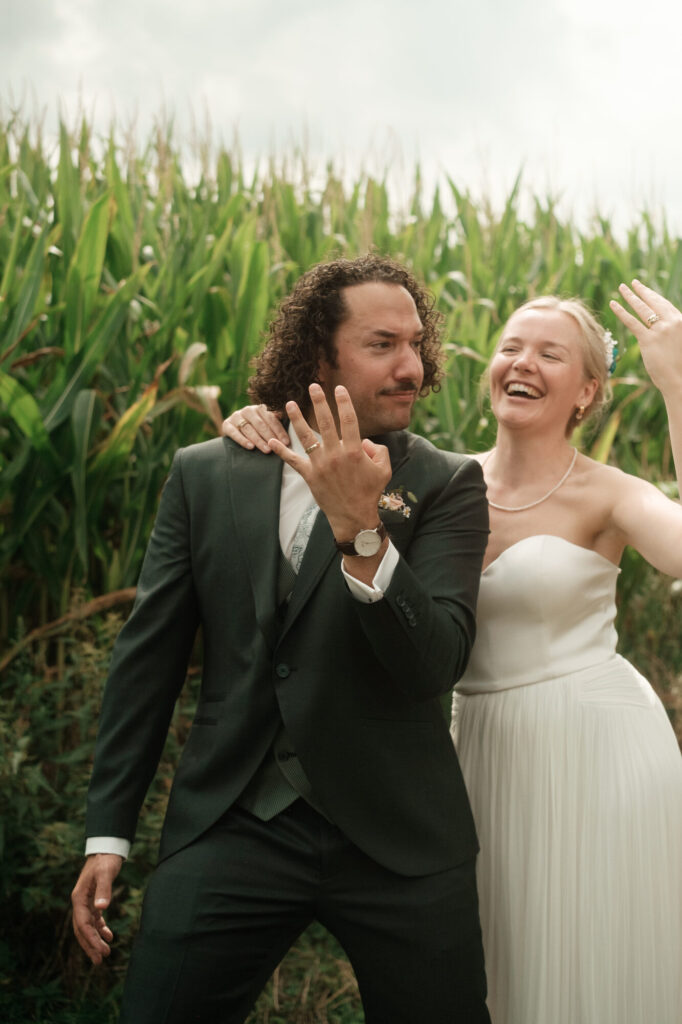 Brautpaar winkt vor dem Maisfeld, Hochzeit Anne & Phil auf dem Hof Gottschalk in Helpsen